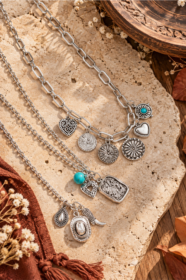 Close up of silver concho, coin, heart and turquoise charms on stackable necklaces
